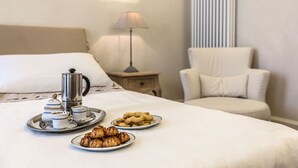 Una cama bien hecha con una bandeja de pasteles y una instalación para café.