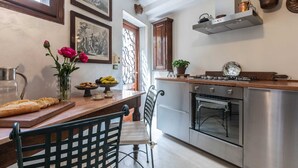 Cozinha com bancada de madeira, fogão e pia. Há flores na mesa e um vaso com uma planta.