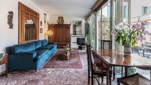 Uma sala de estar com um sofá azul, um armário de madeira e uma mesa de jantar com cadeiras.