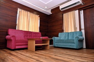 A room with two sofas, a wooden coffee table, and an air conditioning unit.