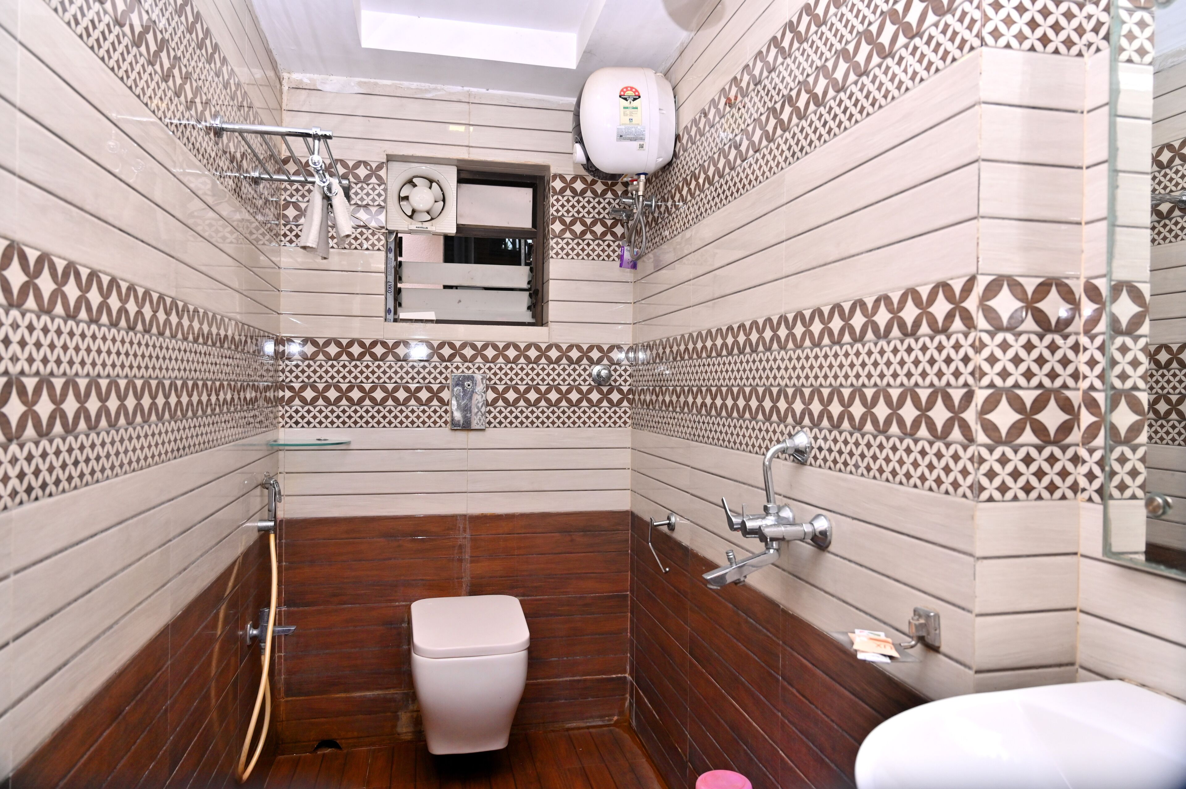 A bathroom with patterned tiles, a toilet, a sink, a shower, and a towel rack.