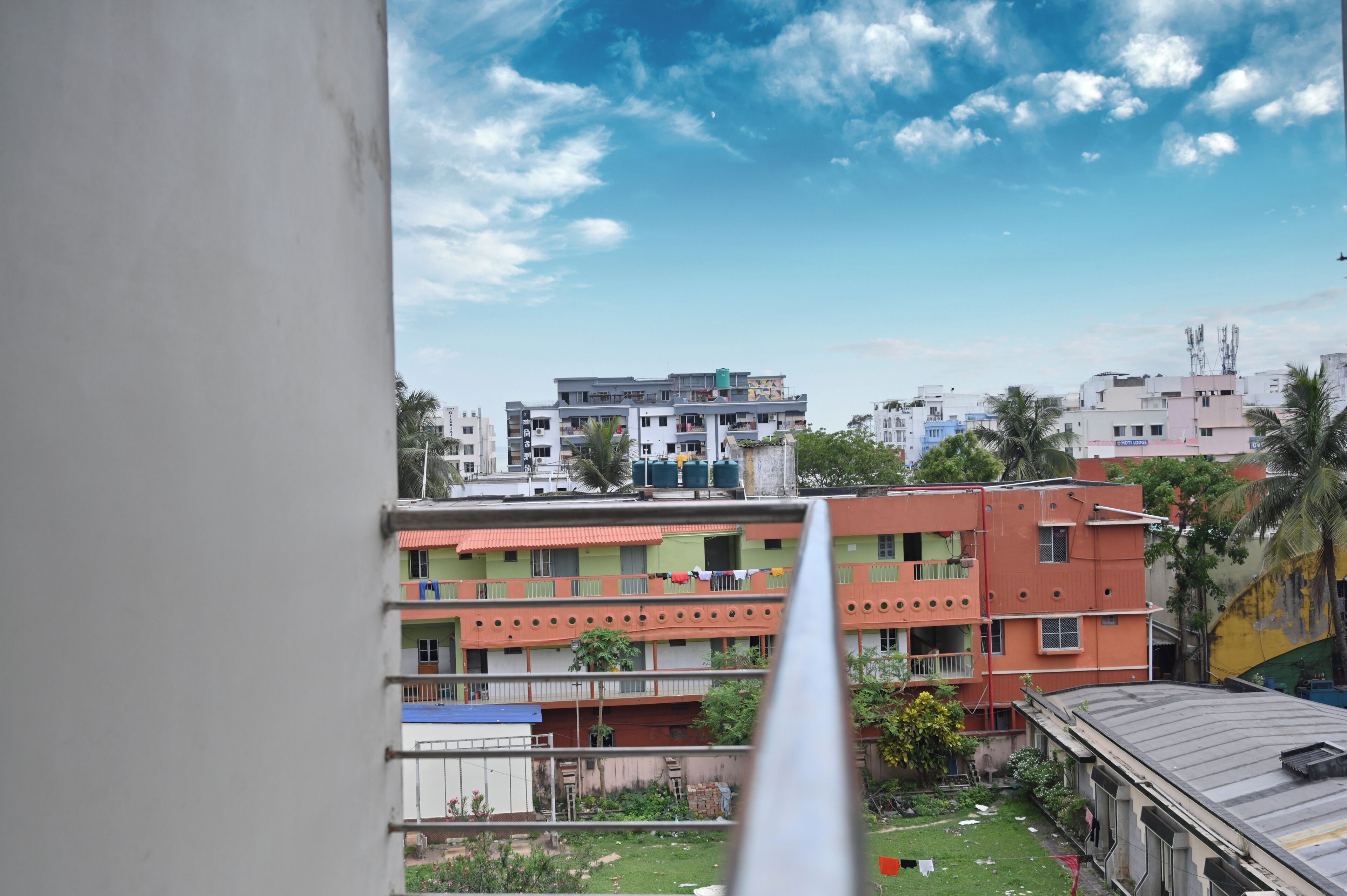 A multi-story building with balconies, a clear sky, and a view of a residential area.
