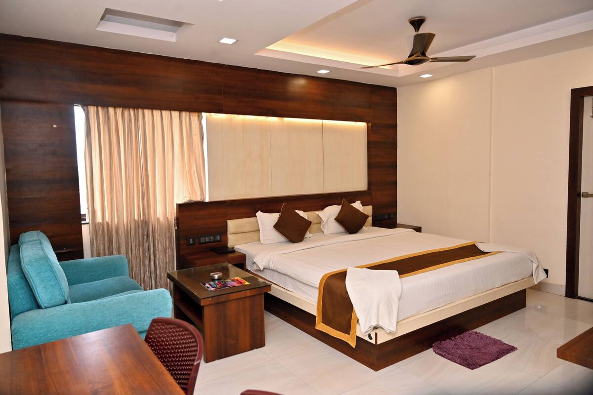 Una habitación de hotel moderna con una cama grande, un sofá, un escritorio y un ventilador de techo.