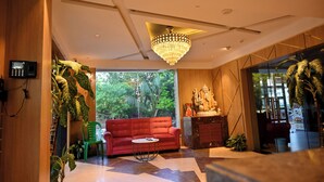 A modern interior with a red sofa, a chandelier, and potted plants.