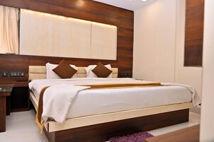 A modern bedroom with a large bed, wooden headboard, bedside tables, and a built-in wardrobe.