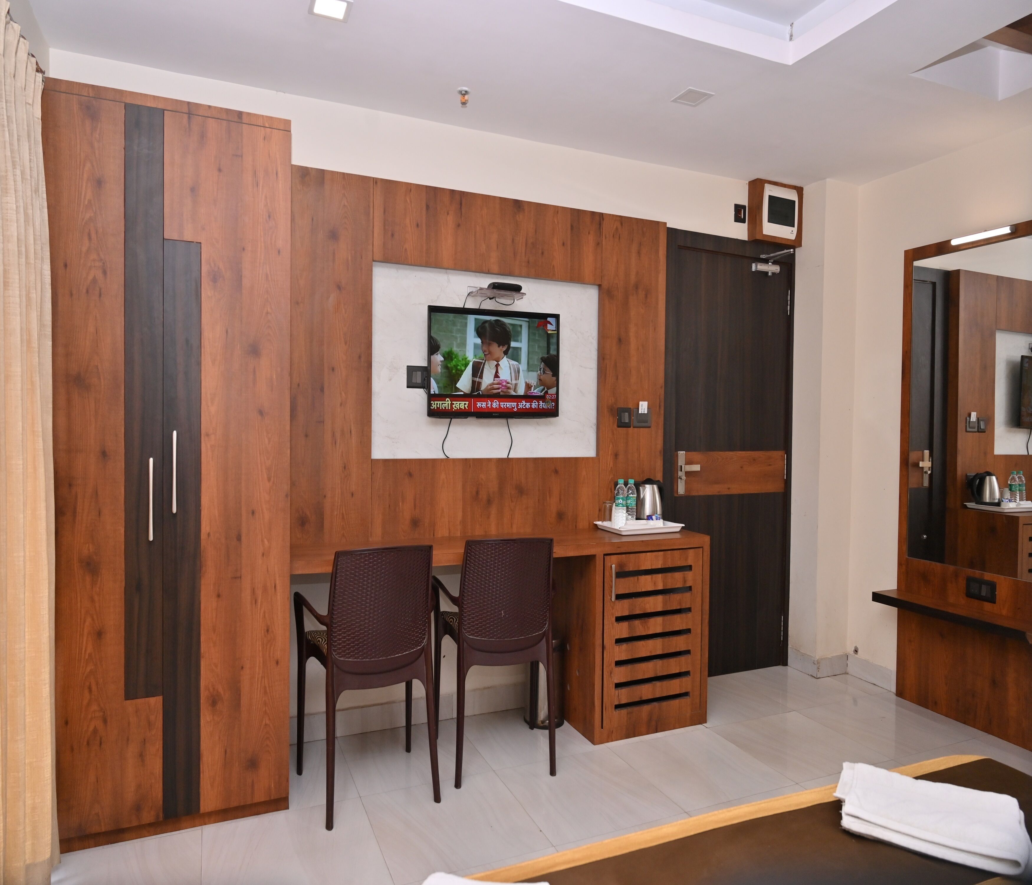 A modern room with wooden cabinetry, a television mounted on the wall, two chairs, and a small table with a tray.