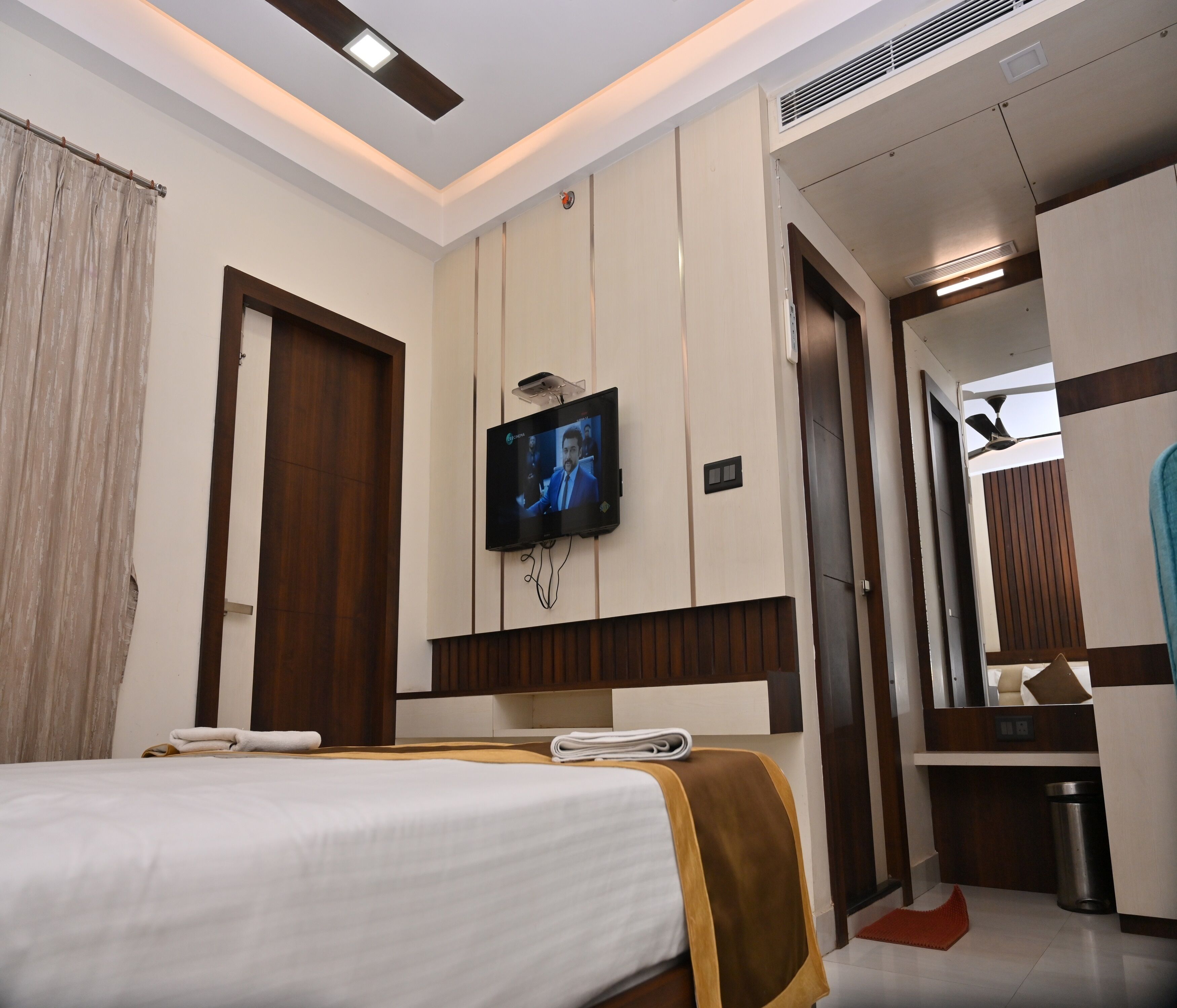Une chambre d’hôtel avec un lit, un téléviseur fixé au mur, une porte et un miroir.