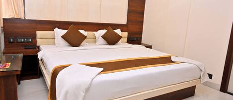 Una habitación de hotel moderna con una cama grande, cabecera de madera y una mesita de noche con lámpara.