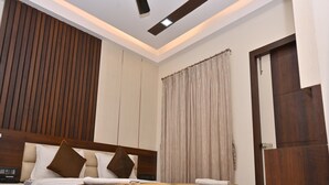 A modern bedroom with a wooden headboard, a ceiling fan, and a large window with curtains.