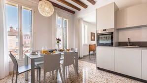 Une cuisine moderne avec des meubles blancs, un four encastré et un coin repas comprenant une table et des chaises.