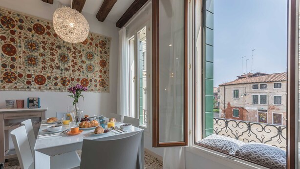 Un coin repas avec une table mise pour le petit-déjeuner, un mur décoratif et une vue sur la ville par une fenêtre.