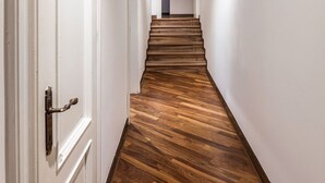 Een gang met houten vloer, witte wanden en een houten plafond.