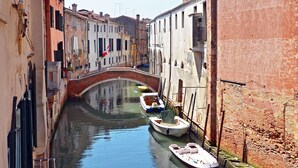 A narrow canal flanked by historic buildings with a bridge, boats docked along the water.