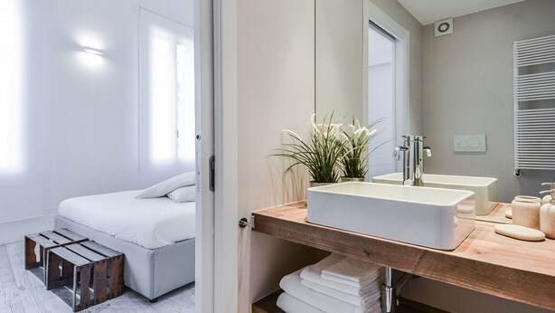 Une salle de bain moderne avec un grand miroir, un meuble-lavabo en bois et une baignoire blanche.