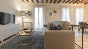 Een moderne woonkamer met een bank, salontafel, televisie en kunstwerk.