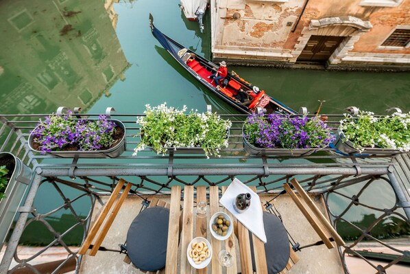 A gondola on a canal, with a table and potted plants in the foreground.