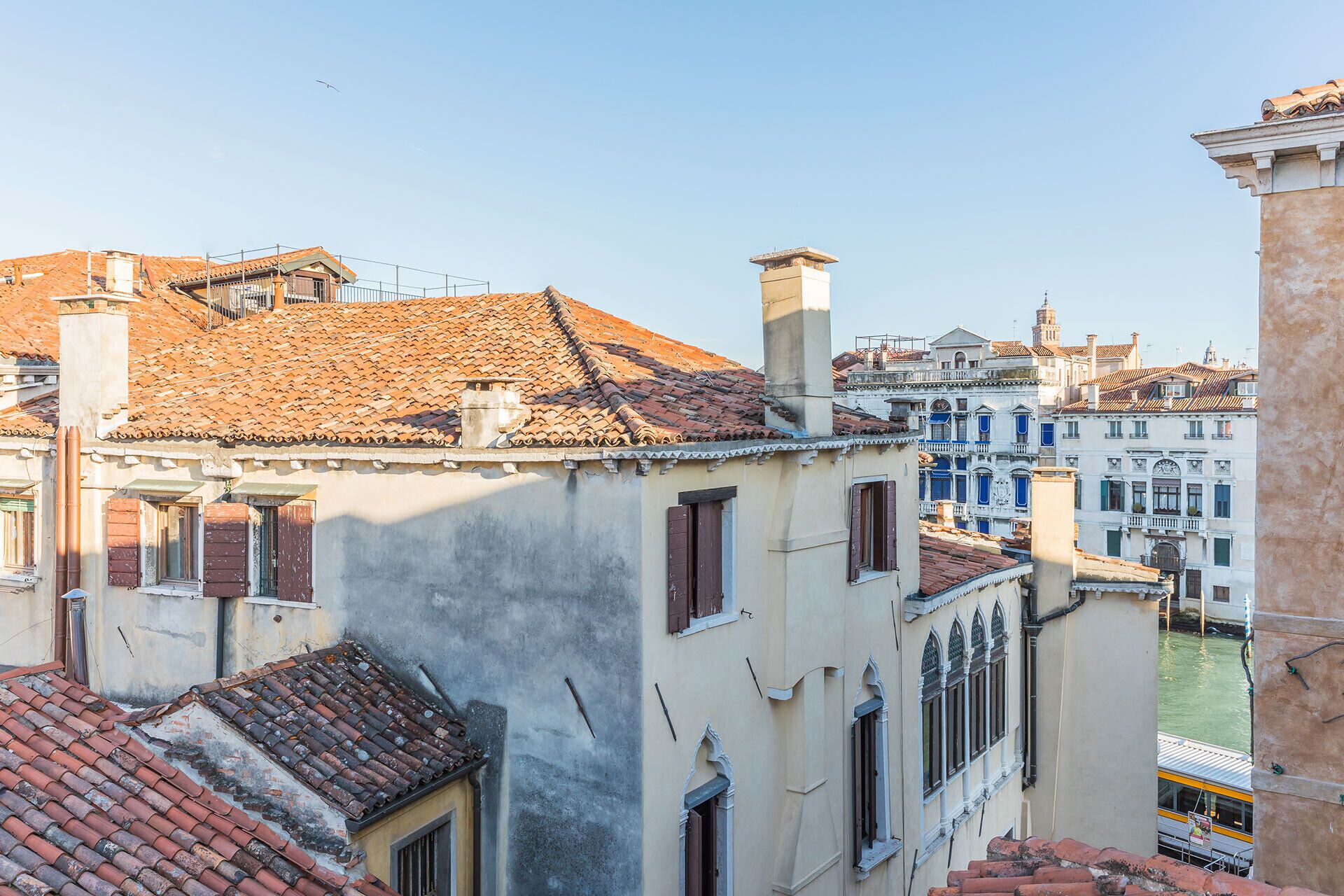 Vista de um edifício histórico com telhado de azulejos, varanda e rio ao fundo.