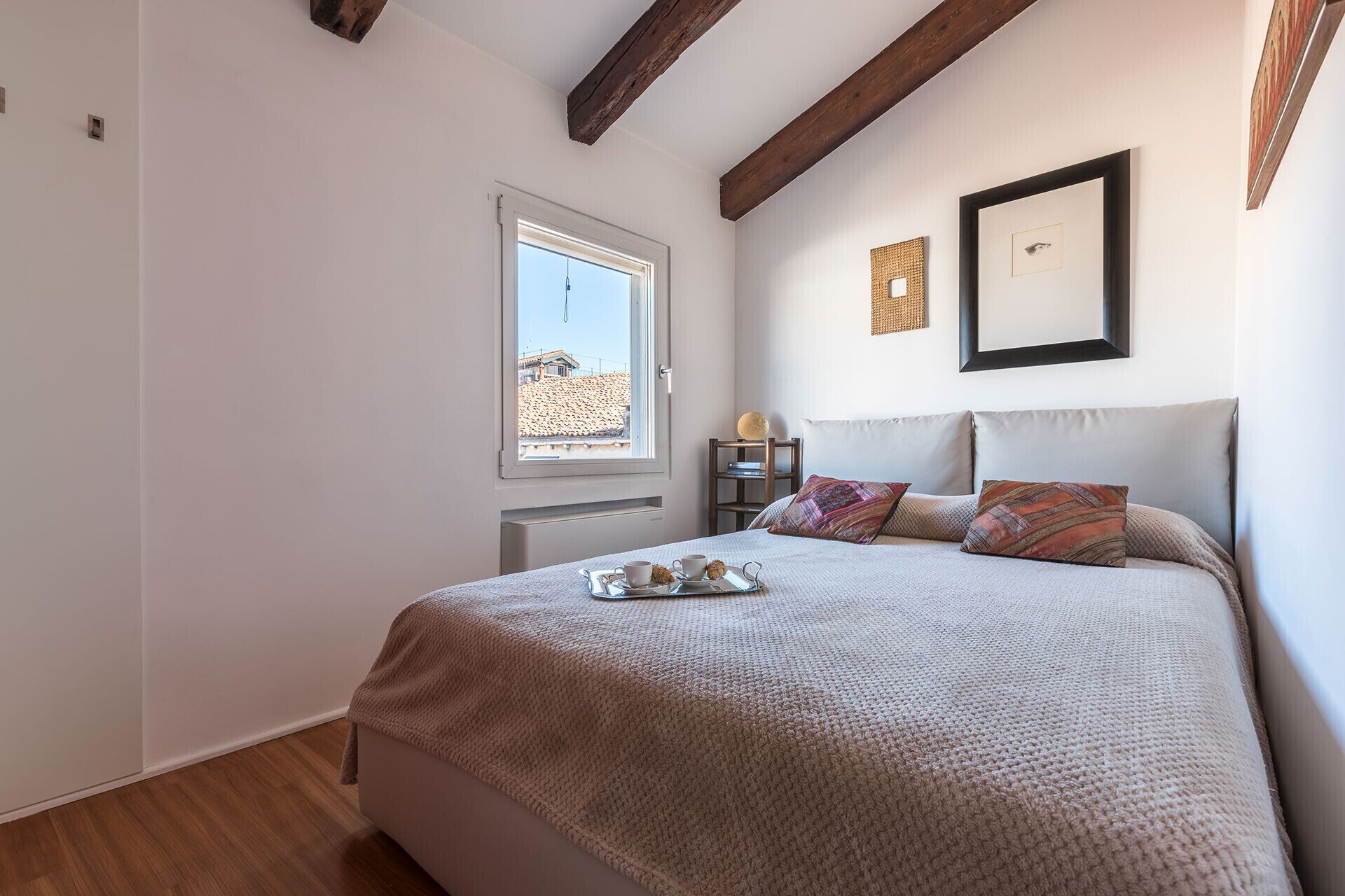 Un dormitorio con una cama grande, una ventana y vistas a edificios.