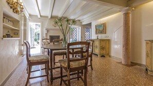 Un coin repas avec une table ronde, quatre chaises en bois, un vase de fleurs et un lustre.