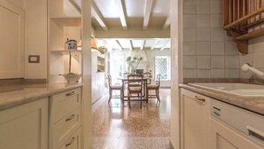 Une cuisine avec des meubles blancs, un plan de travail en marbre et un coin repas comprenant une table et des chaises en bois.