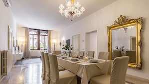 A dining room with a chandelier, a large ornate mirror, and a table set for six. - Spacious and Charming Apartment Near Fenice Theatre (Venecia)