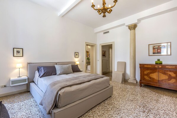 A bedroom with a bed, bedside lamps, a dresser, and a chandelier.