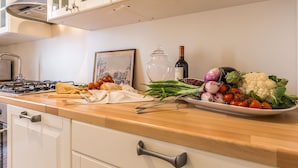 A kitchen counter with a gas stove, a wine bottle, and various fresh vegetables. - Spacious and Charming Apartment Near Fenice Theatre (Venecia)