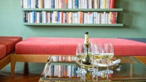 A glass table with a bottle and glasses of white wine, a red sofa, and a bookshelf in the background. - Quiet and Eclectic Apartment next to the Fenice Theatre (Venecia)