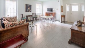 Ein Wohnzimmer mit einem Holzsofa, einem runden Tisch mit Stühlen, einem Fernseher und einer Tür.
