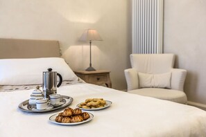 A neatly made bed with a tray of pastries and a coffee setup. - Elegant 6-bedroom penthouse with a terrace and a view of the canal (Venecia)