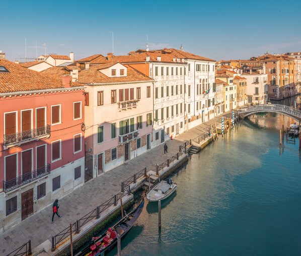 A canal with buildings on one side and a bridge in the distance. - Elegant 6-bedroom penthouse with a terrace and a view of the canal (Venecia)