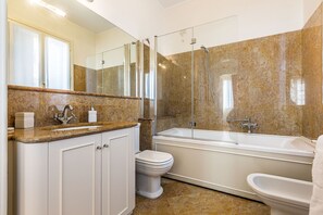 A modern bathroom with a marble vanity, a glass-enclosed shower, and a freestanding bathtub. - Elegant 6-bedroom penthouse with a terrace and a view of the canal (Venecia)