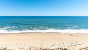 Ein Strand mit blauem Himmel, ruhiger See und einem eingezäunten Bereich mit einem Weg zum Wasser.