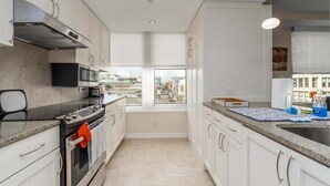 Una cocina moderna con un amplio ventanal, electrodomésticos de acero inoxidable y armarios blancos.