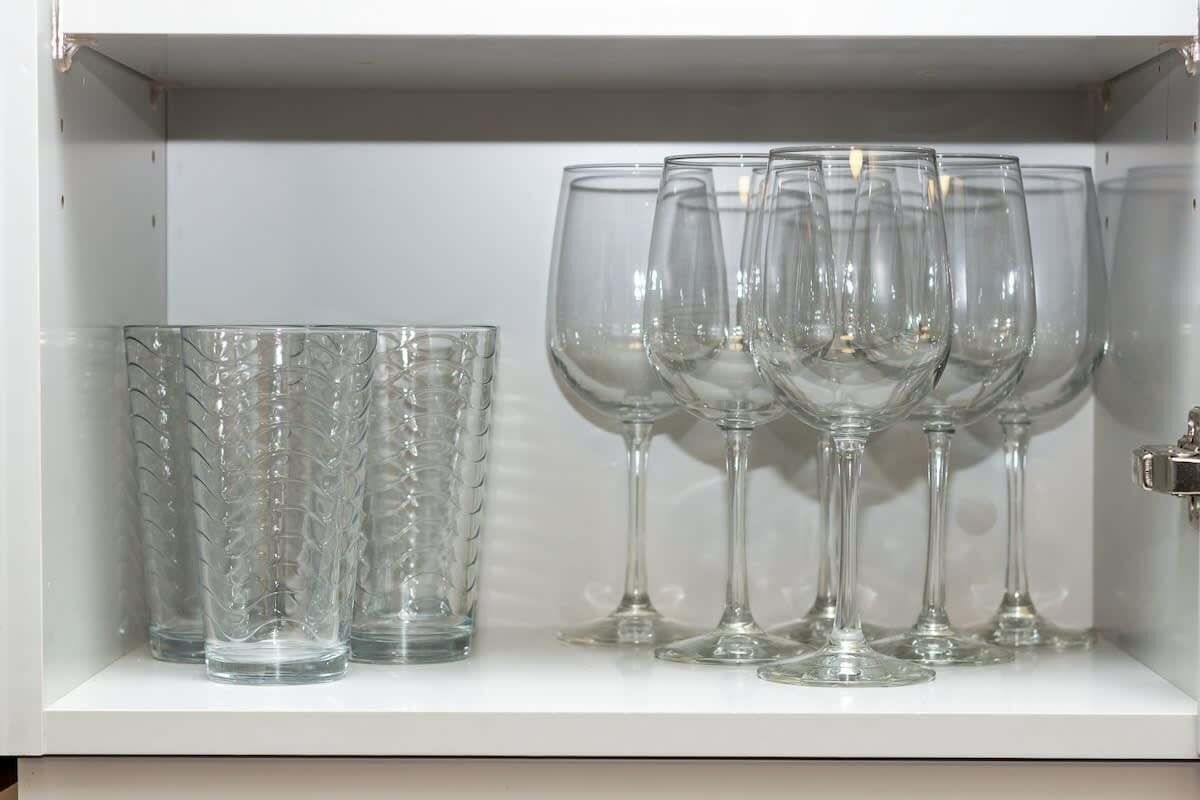 Un meuble vitré contenant de la verrerie transparente, notamment un verre texturé et plusieurs verres à pied.