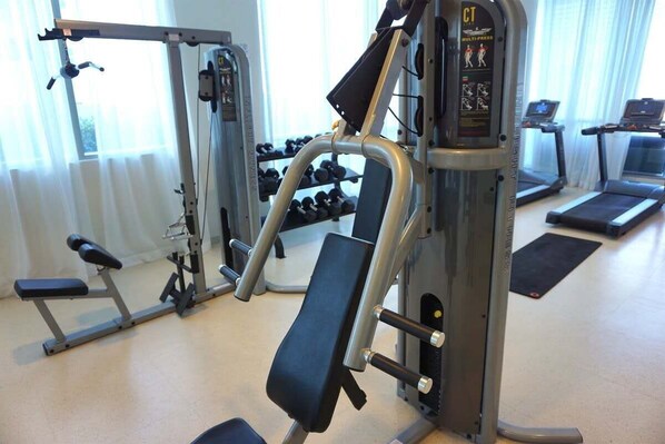 Un gimnasio con máquinas de pesas, cintas de correr y mancuernas.