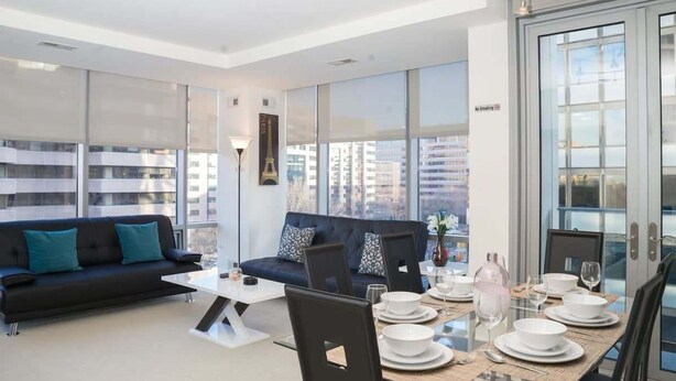 A modern living room with a sofa, dining table, and chairs.