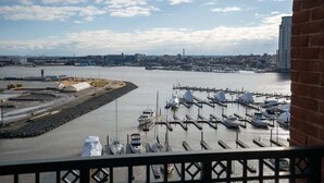 Uma marina com barcos atracados, um horizonte urbano ao fundo e um céu limpo.