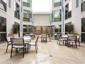 A courtyard with outdoor seating, potted plants, and a wooden wall.