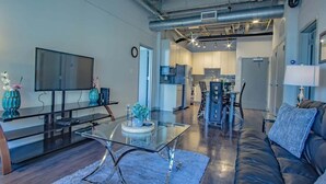 A modern living room with a glass coffee table, a leather sofa, and a flat-screen TV.