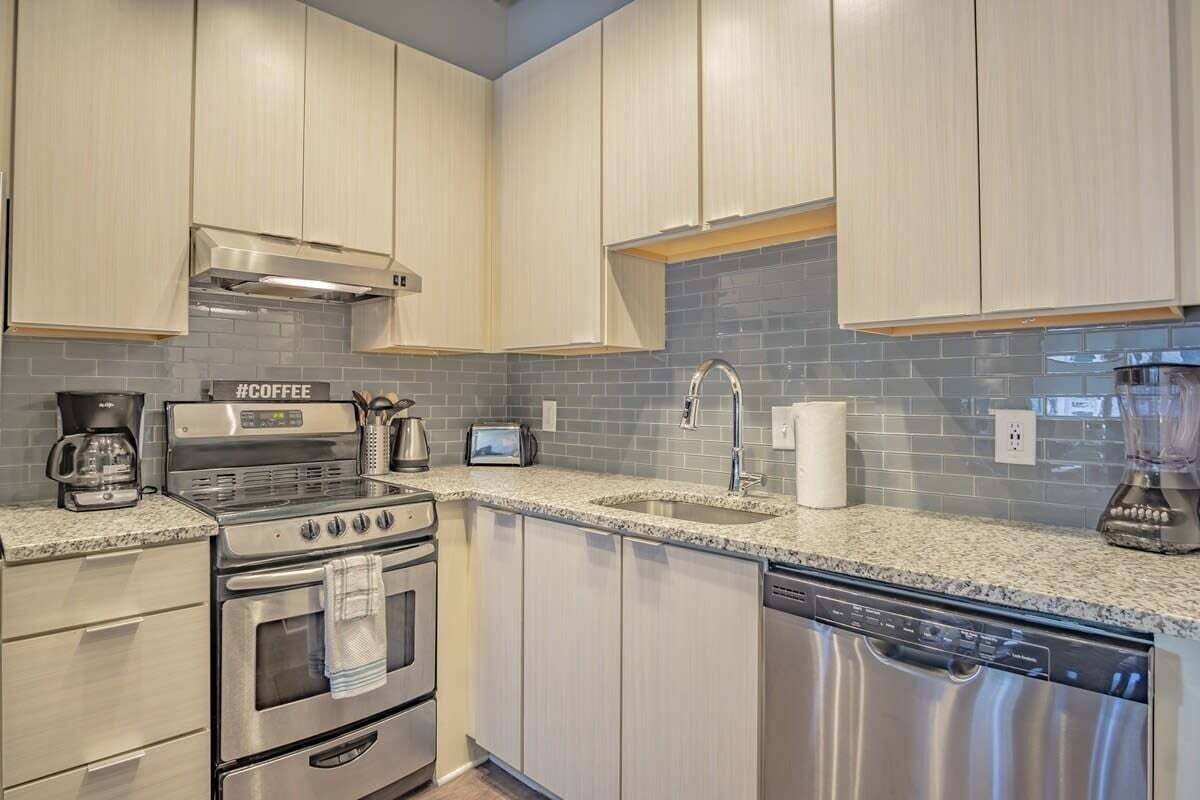 A modern kitchen with stainless steel appliances, a granite countertop, and light-colored cabinetry.