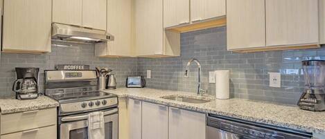 A modern kitchen with stainless steel appliances, a granite countertop, and light-colored cabinetry.