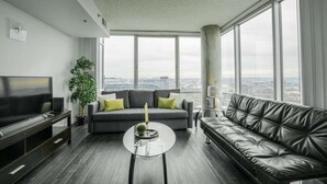 A modern living room with a large window, a sofa, a TV, and a coffee table. - 2br Furnished Apartment In Baltimore Downtown 2 Bedroom Apts by RedAwning (Baltimore)