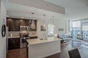 A modern kitchen with dark cabinets, stainless steel appliances, and pendant lighting. - High Rise 2 Bedroom apartment in a Great location 2 Apts by RedAwning (Atlanta)