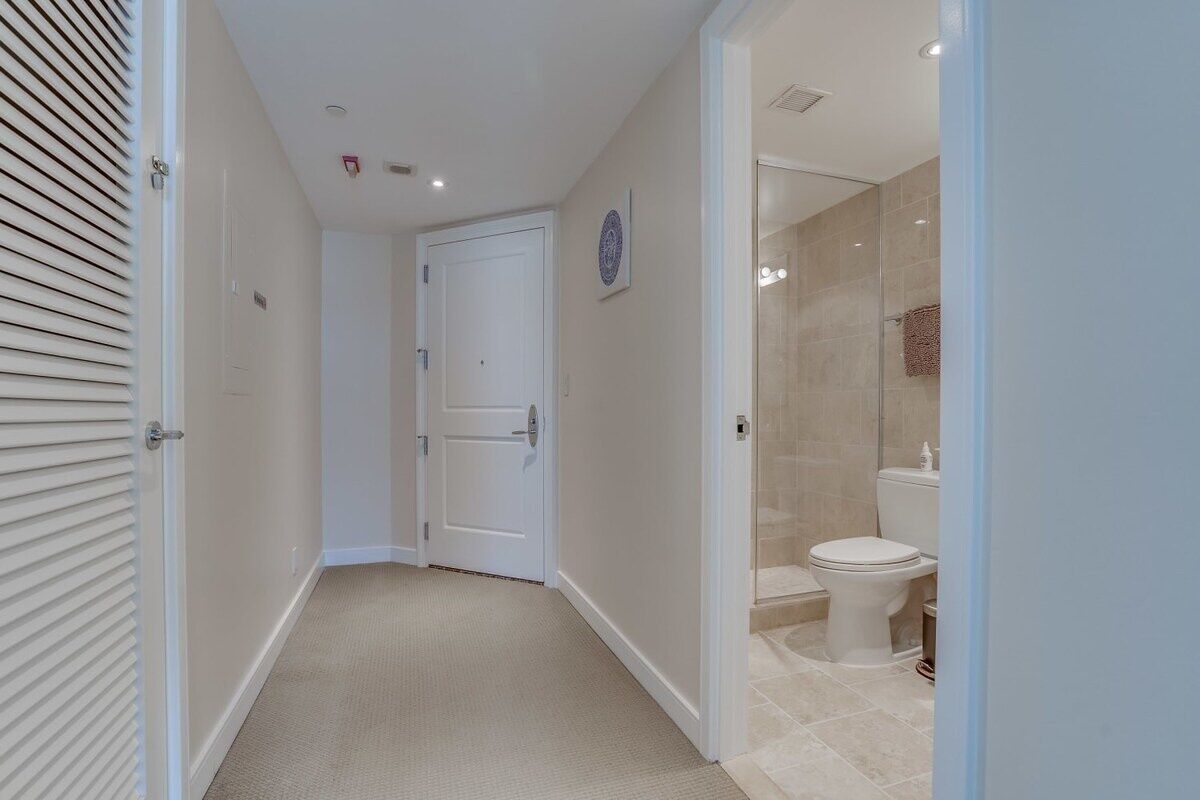 Ein Flur, der zu einem Badezimmer mit Toilette und Duschbereich führt.