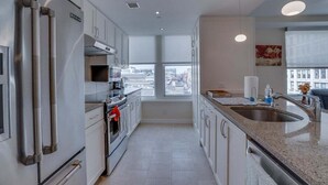 Eine moderne Küche mit Edelstahlgeräten, einem großen Fenster und Blick auf die Stadt.