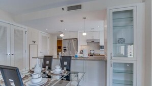 Eine moderne Küche mit weißen Schränken, einem Glastisch und einem Einbauschrank mit Glastüren.