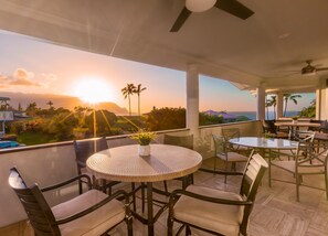 Ein Balkon mit rundem Tisch, Stühlen und einem Blumentopf.