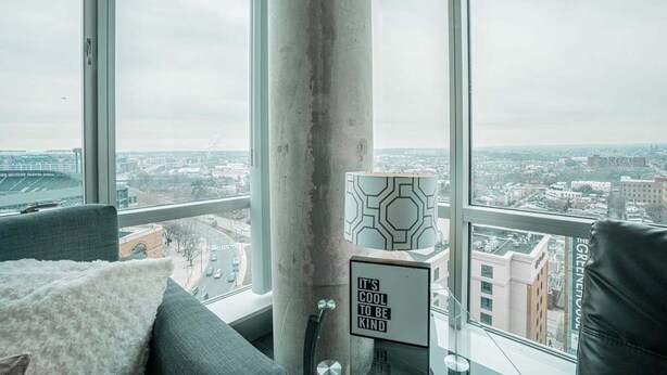A modern room with a large window, a view of a cityscape, a concrete pillar, and a sign with a motivational message.
