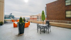 A rooftop terrace with seating, a table, and a view of the city skyline.